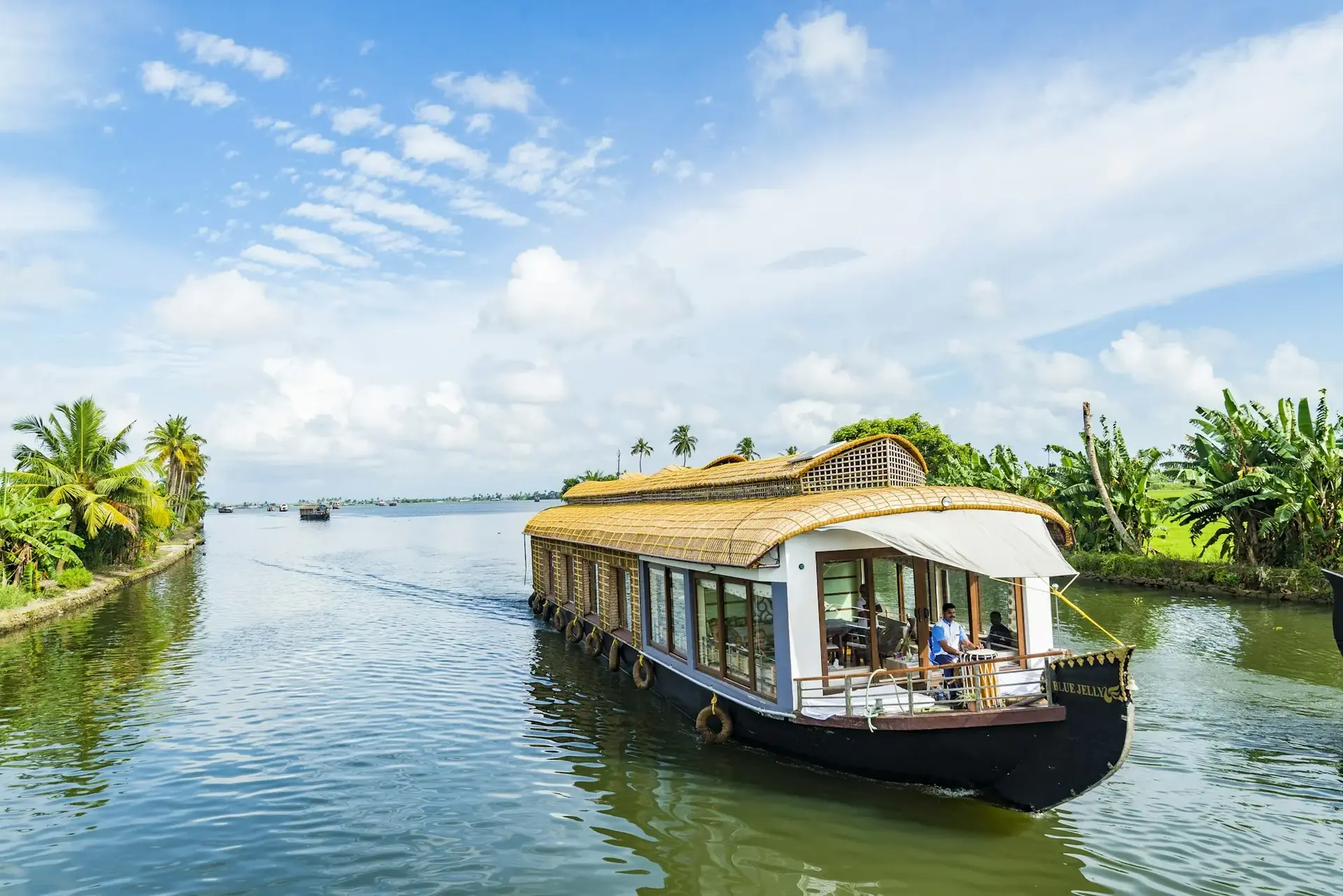 Houseboat cruising the Kerala backwaters under a clear blue sky